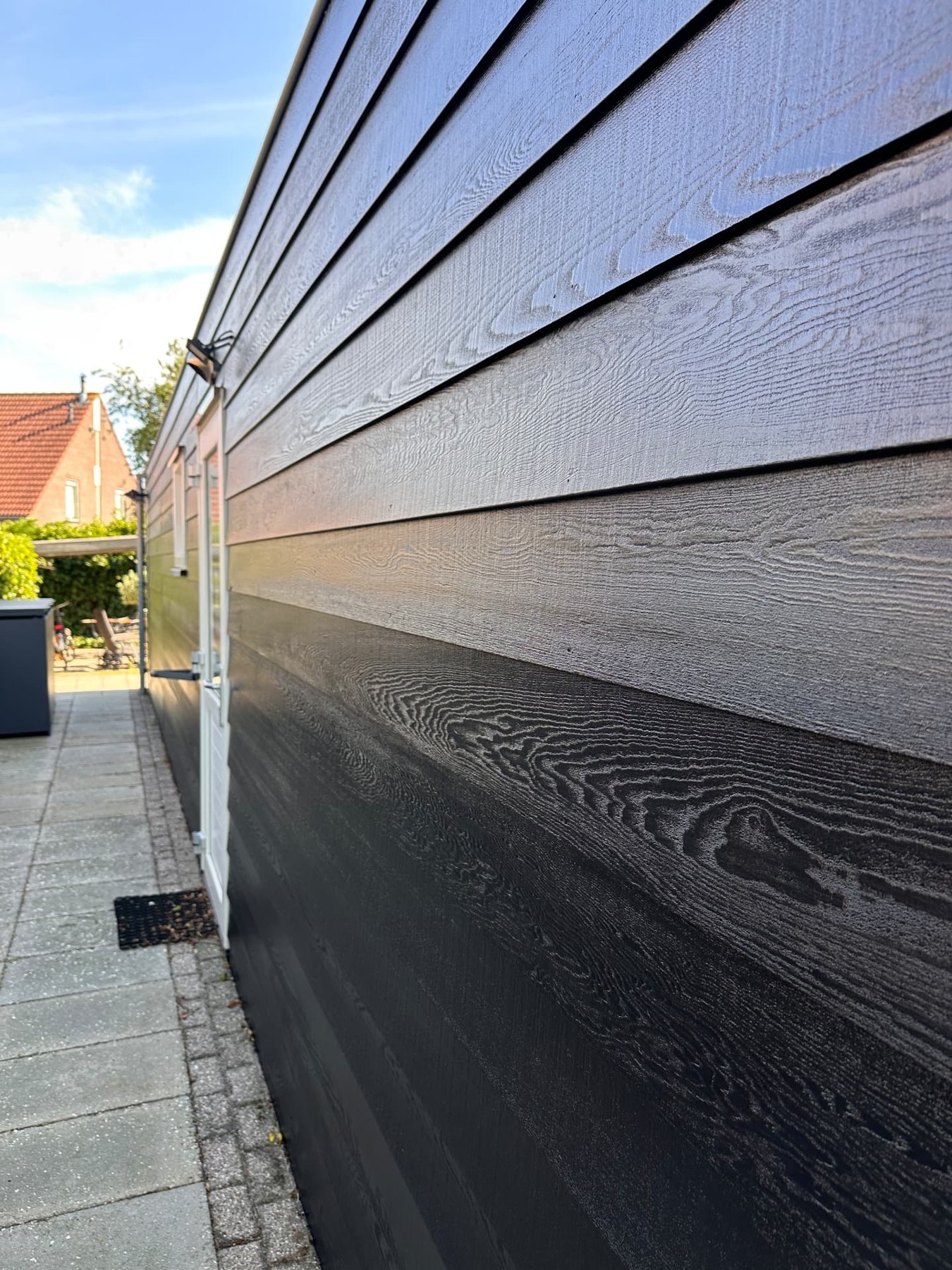 Zwart geschilderde horizontale houten gevelplanken met zichtbare houtstructuur