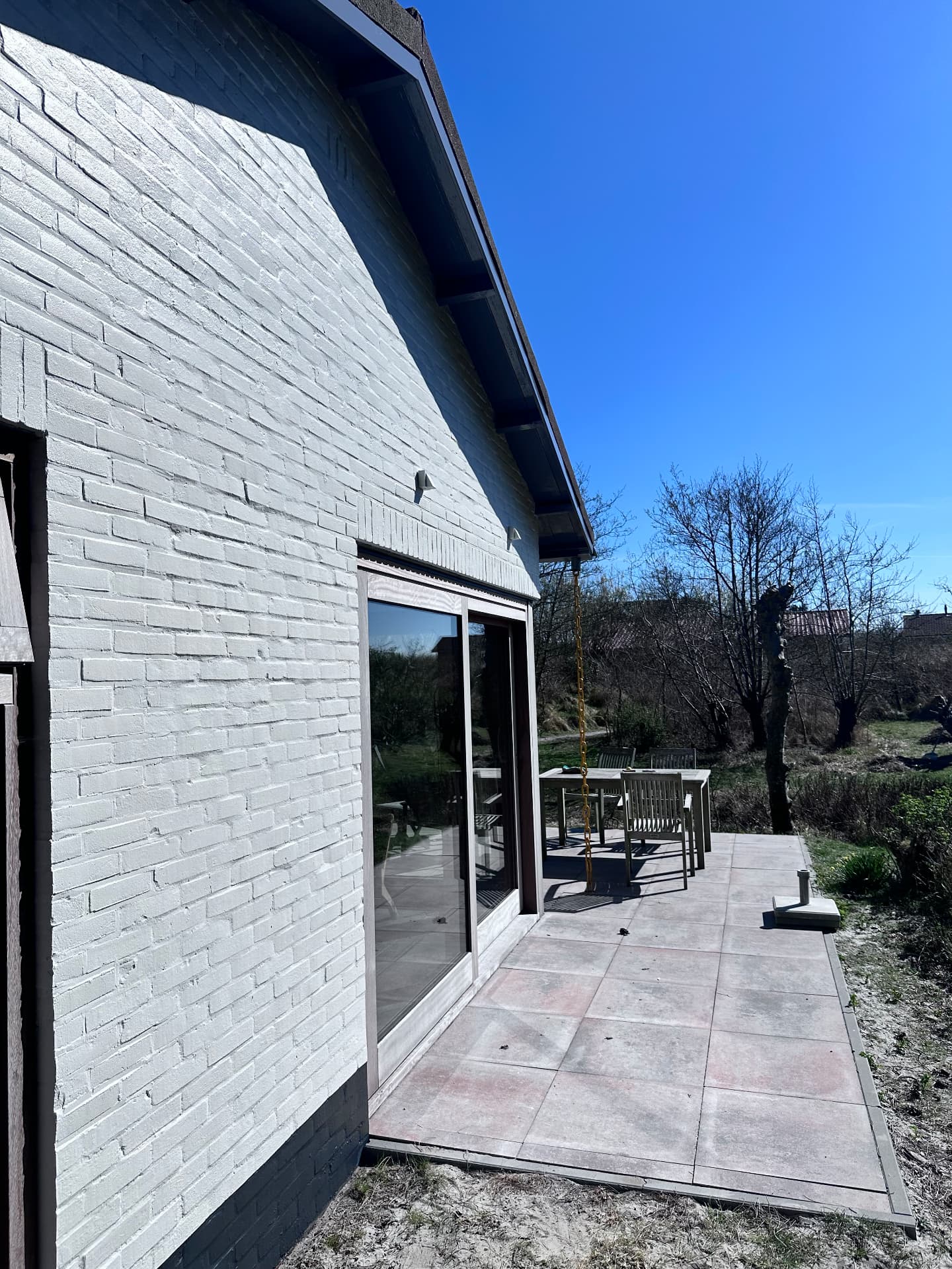 Wit geschilderde bakstenen gevel met tuinzicht en schuifpui