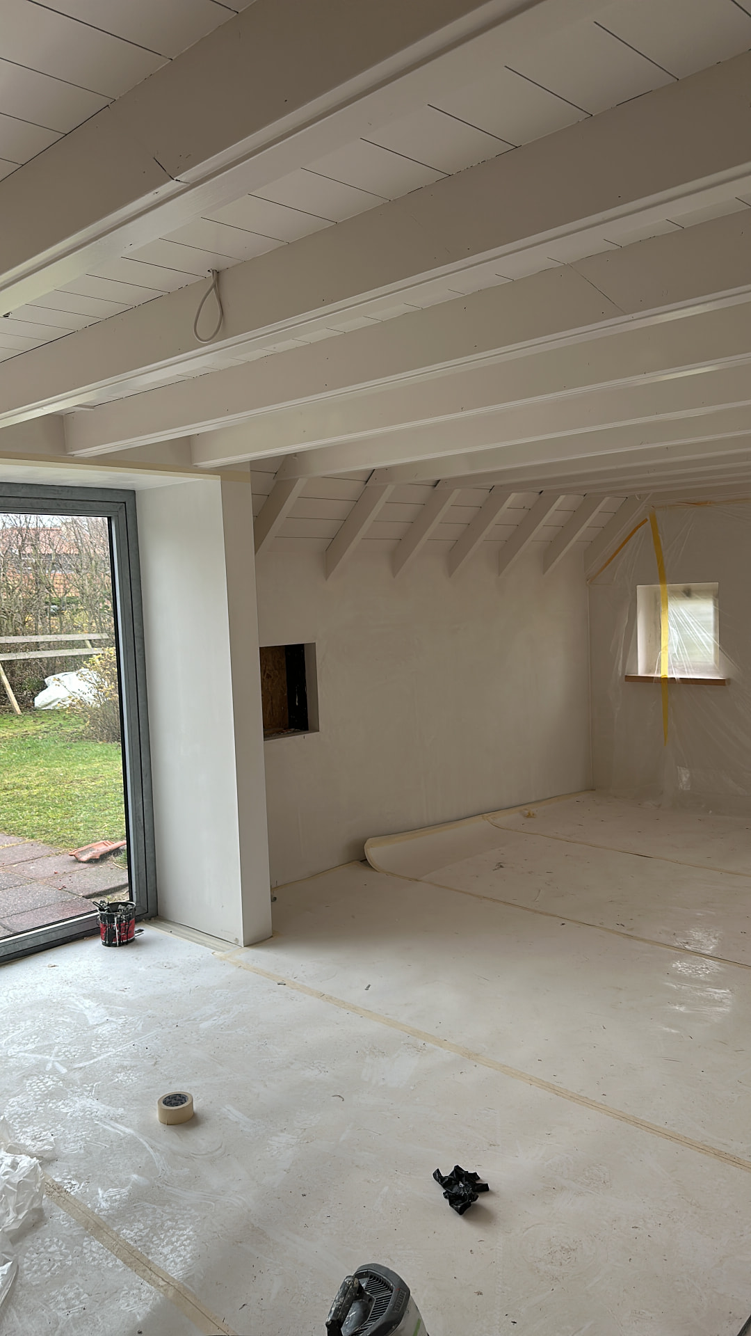 Licht geschilderde plafondbalken en houten plafond in een ruimte tijdens renovatie