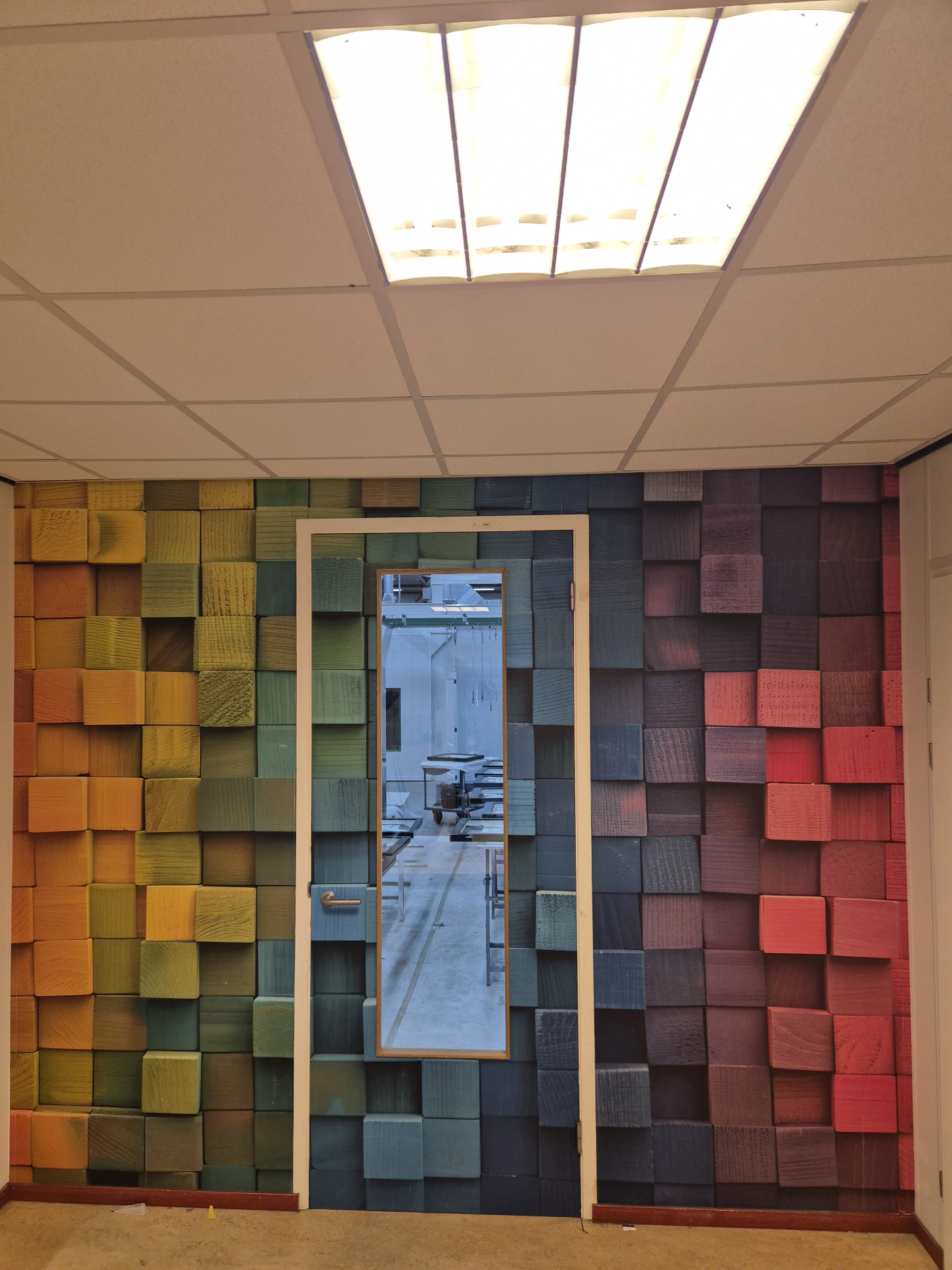 Kantoorwand en deur volledig bekleed met fotobehang van houten blokken in een kleurverloop